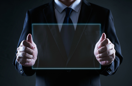 Businessman holding a clear glass empty virtual screen template, notice purpose and information using ideal concept .の写真素材