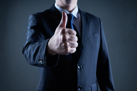 Successful businessman gives thumb up pose. Likes and positive feel. Gesture good and agree , finger agreementの写真素材