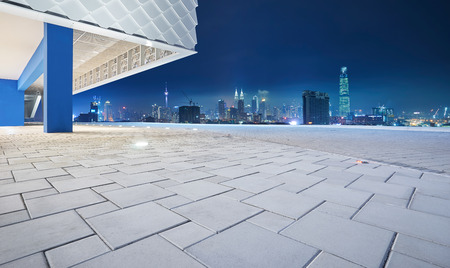 Perspective view of empty floor with modern building exterior and cityscape skyline . Night scene .の写真素材