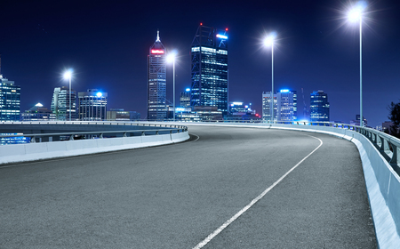 High speed corner overpass asphalt road with Perth cityscape , night scene .の写真素材