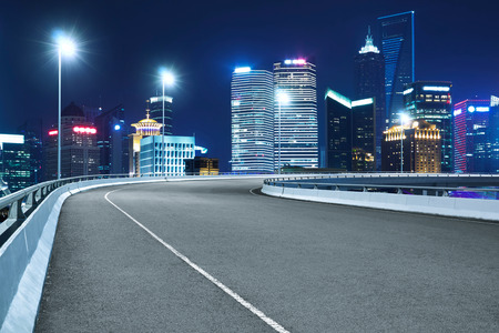 High speed corner overpass asphalt road with modern skyscraper , night scene .の写真素材