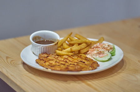 Chicken chop with french fries ,salad and black pepper sauce on wood table .の写真素材
