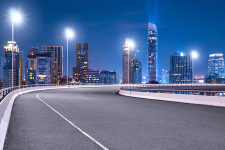 High speed corner overpass asphalt road with Bangkok cityscape , night scene .の写真素材