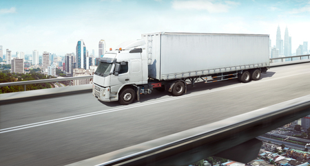 Truck with container on high speed overpass with city skyline , cargo transportation concept.の写真素材