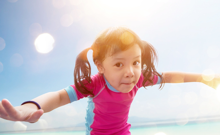 Cute little girl wearing pink swimsuit posing on the beach,summer vacation concept .の写真素材