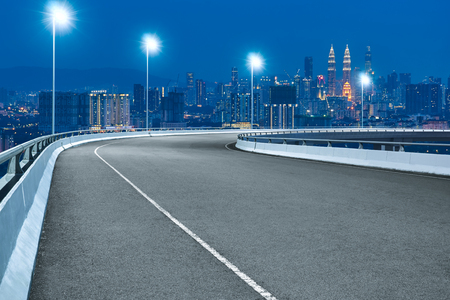 High speed corner overpass asphalt road with Kuala Lumpur cityscape , night scene .の写真素材