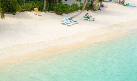 Beautiful beach panorama view over a Rawa island. Woman with hat relaxing and reading on chair beach , Malaysia .の写真素材