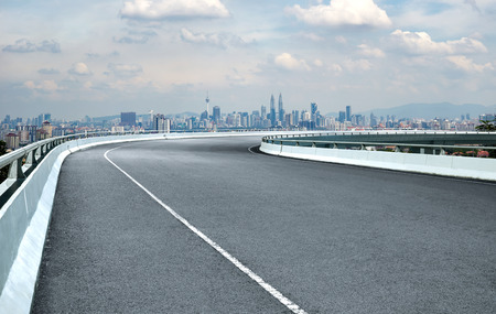 Curvy flyover highway asphalt road with cityscape skyline , noon scene .の写真素材