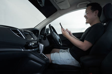 Asian man driver using smart phone in car .の写真素材