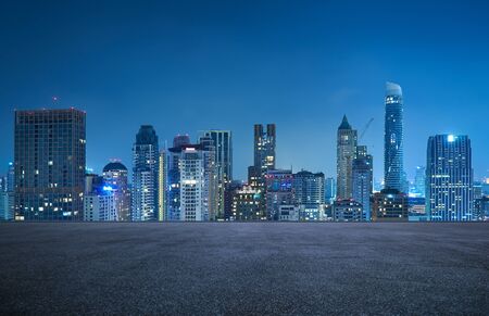 Bangkok urban cityscape skyline night scene with empty asphalt floor on frontの写真素材