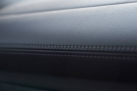 Close up of black leather detail with light and shade of a modern car interiorの写真素材