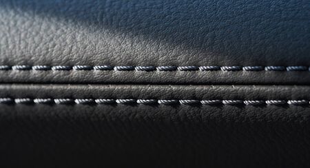Close up of black leather detail with light and shade of a modern car interiorの写真素材