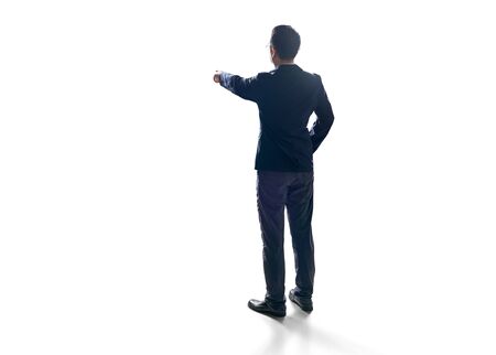 Rear angle view businessman pointing finger up to the front, isolated on white background.の写真素材