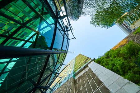 Low angle shot of modern glass buildings and green with clear sky background.の写真素材