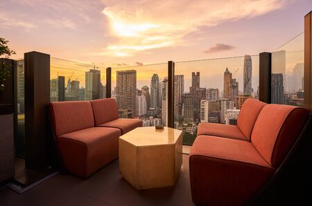 Comfortable sofa unit on rooftop bar and restaurant area with beautiful sunset cityscape view .の写真素材