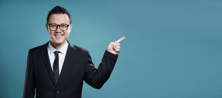 Businessman in suit smile and finger point to the right . Horizontal format