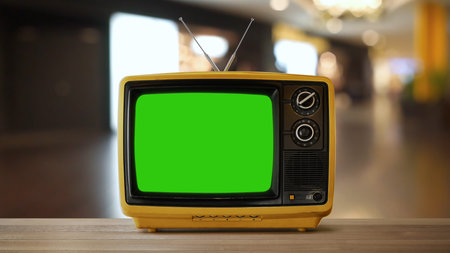 Yellow orange color old vintage retro Television on wood table with green screen .