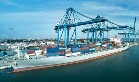 Logistics container cargo ship with working crane bridge in import export terminal port, international logistics transport industry background, Panorama arial view.の写真素材