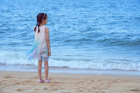 Lovely asian little girl in a pink shirt on tropical beach, travel vacation concept.の写真素材