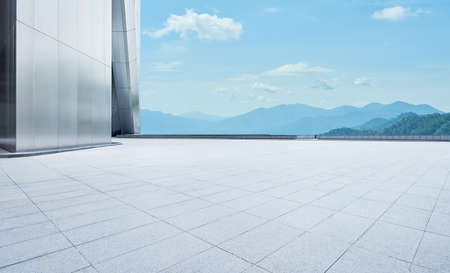 Perspective view of empty concrete tiles floor with modern architecture and beautiful landscape, Morning sceneの写真素材