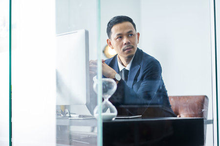 Young Asian employee looking outside during working day in officeの写真素材