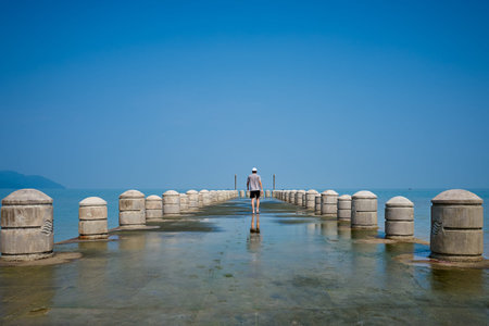 Tourists leisurely walk on the pier at the Batu Ferringhi beach of Penang Islandの写真素材