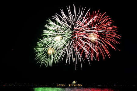 colorful fireworks reflecting over the waterの写真素材