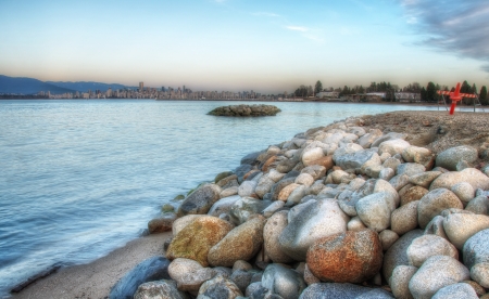 Vancouver skyline can be seen in the distance with rocks, pylons and water in the foreground の写真素材
