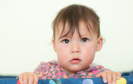 Baby with Big Cute Eyes standing in a play pen