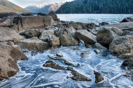 Ice along side of lake with distant mountainsの写真素材