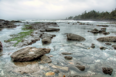 Clear water along a rocky coast with large waves in backgroundの写真素材