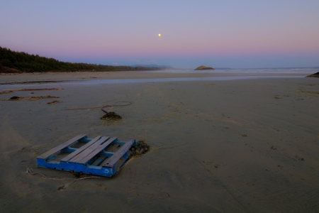 Moon in the distance with long beach at dusk and skidの写真素材