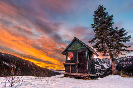 Snowy shack with tree in a ski resort at sunsetの写真素材
