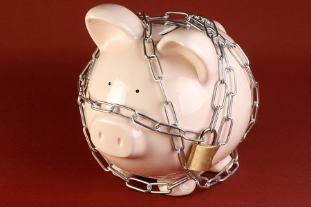 security concept pink piggy bank wrapped in chains and padlockedの写真素材