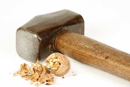 old sledge hammer and crushed walnut on a white background, excess force conceptの写真素材