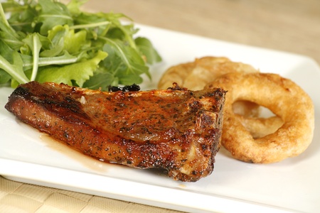 grilled lamb cutlet with onion rings and rocket lettuceの写真素材