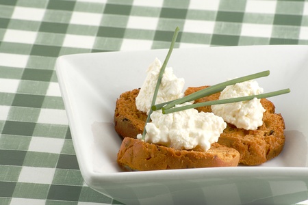 Three brushetta with cottage cheese and chives on a white dishの写真素材