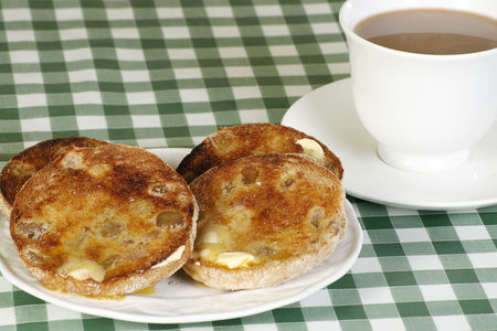 toasted english muffins and tea on a green gingham clothの写真素材