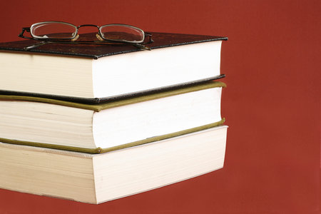 three books with spectacles on a red background