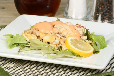 Crab salad on a white plate with lemon and sauceの写真素材