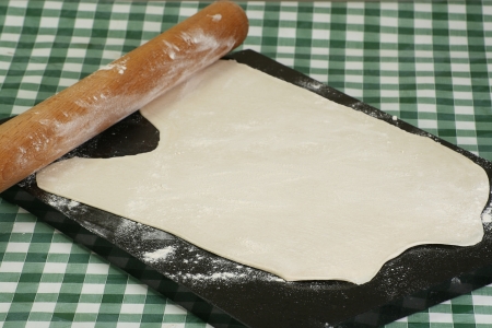 Rolled raw pastry on a floured marble board with a rolling pinの写真素材