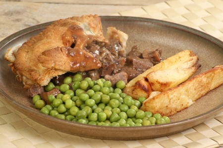 Slice of home made steak and kidney pie with peas and roast parsnipsの写真素材
