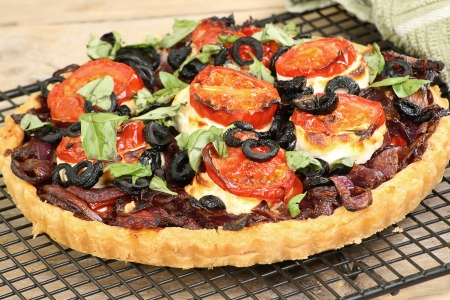 caramalised onion and goats cheese tart with tomato and olivesの写真素材