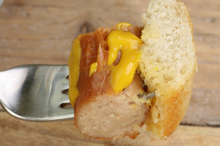  piece of hot pork sausage on a fork with mustard                              の写真素材