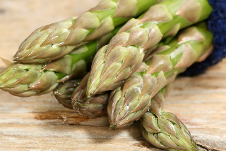     bunch of fresh uncooked asparagus spears on a wooden board                           の写真素材