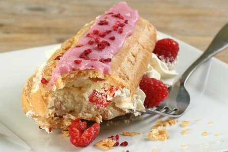 single cream filled eclair with fresh rapberries and raspberry icing