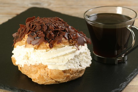 cream filled chocolate choux bun with black coffeeの写真素材