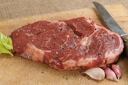 uncooked rib eye steak on a rustic chopping boardの写真素材