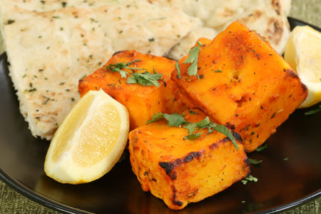 four pieces of marinated paneer cheese with coriander and lemonの写真素材