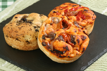 mini italian focaccia breads with tomatoes onion and olivesの写真素材